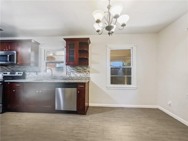 kitchen with baseboards, stainless steel appliances, light stone countertops, and decorative backsplash