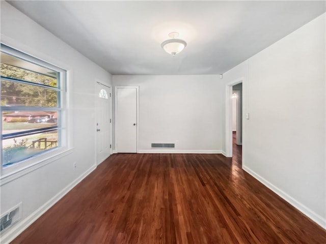 spare room featuring baseboards, visible vents, and wood finished floors