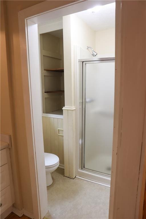full bath featuring a shower stall, toilet, and built in features