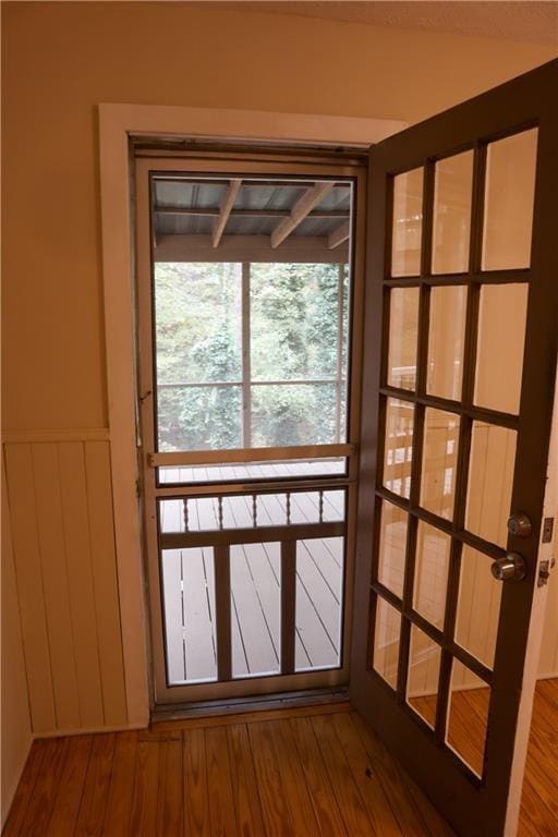 doorway with dark wood finished floors and a wainscoted wall