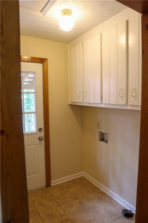 washroom with cabinet space, baseboards, a textured ceiling, and hookup for a washing machine