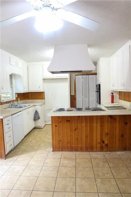 kitchen featuring premium range hood, white dishwasher, a peninsula, stovetop with downdraft, and light countertops
