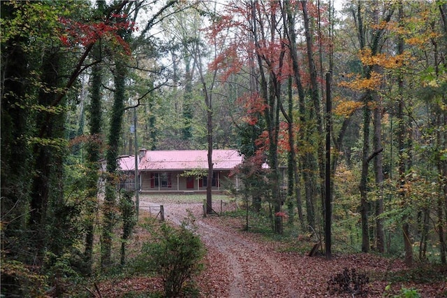 view of front of home featuring a view of trees, metal roof, and a porch