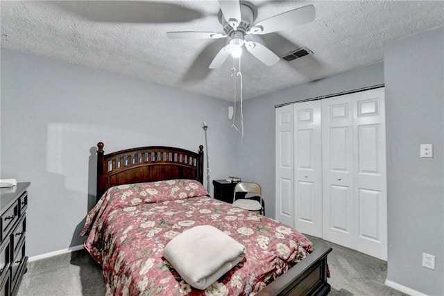 carpeted bedroom featuring ceiling fan, a closet, and a textured ceiling