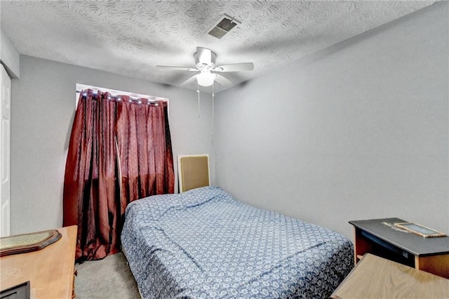 bedroom featuring a textured ceiling, light colored carpet, and ceiling fan