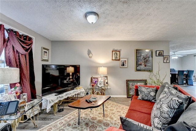 living room with wood-type flooring, ceiling fan, and a textured ceiling