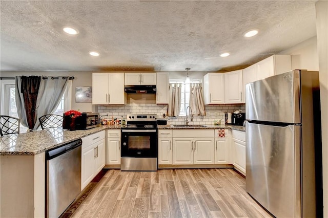 kitchen with white cabinetry, stainless steel appliances, sink, and hanging light fixtures