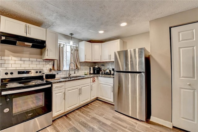 kitchen featuring sink, white cabinetry, dark stone countertops, appliances with stainless steel finishes, and decorative backsplash