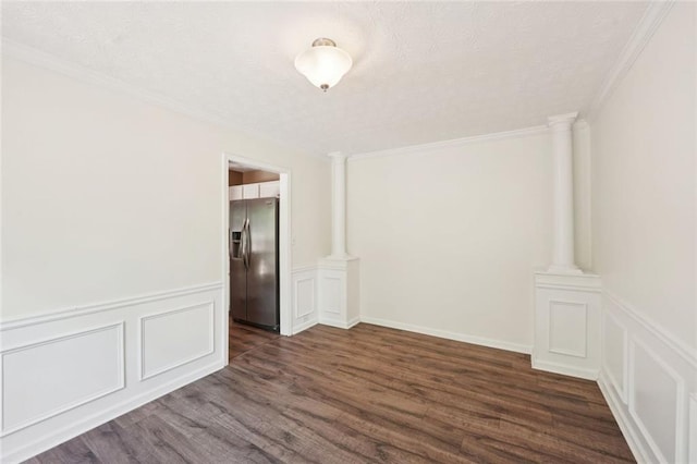 spare room with crown molding, a decorative wall, and dark wood-type flooring