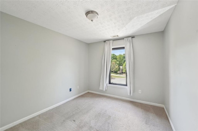 carpeted empty room featuring baseboards, a textured ceiling, and visible vents