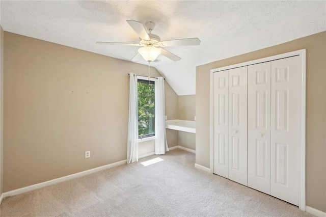 unfurnished bedroom featuring a ceiling fan, a textured ceiling, baseboards, a closet, and carpet
