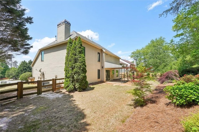 rear view of property with fence, a chimney, and a patio area