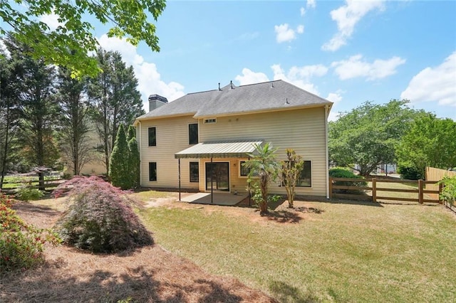 back of property with fence, a chimney, a lawn, and a patio area