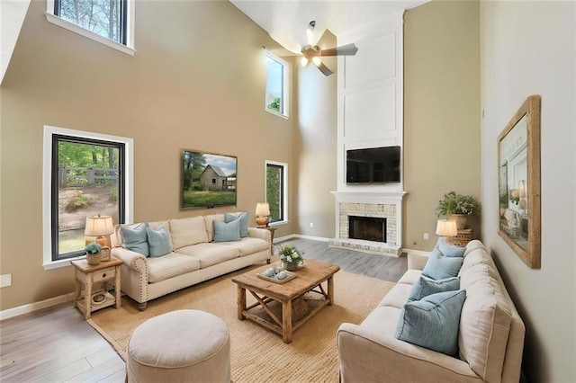 living room featuring light wood-type flooring, plenty of natural light, a high ceiling, and ceiling fan