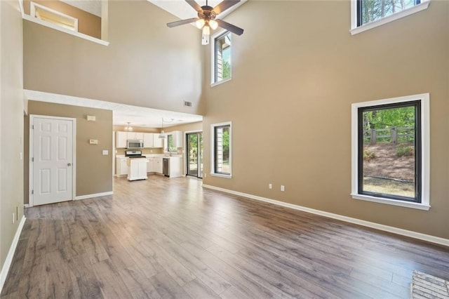 unfurnished living room with baseboards, a high ceiling, and wood finished floors