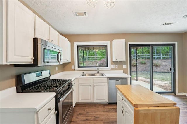 kitchen with a sink, stainless steel appliances, dark wood finished floors, and visible vents