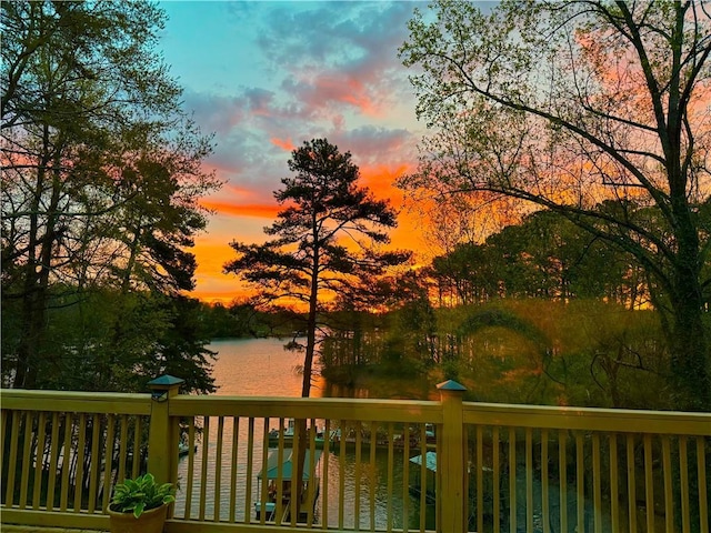 deck at dusk featuring a water view