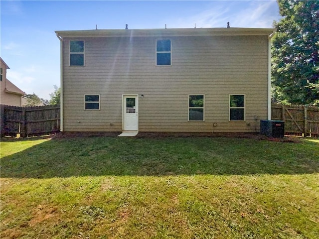 rear view of house with central air condition unit and a yard