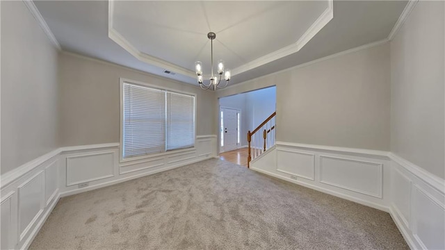 empty room with crown molding, light colored carpet, a tray ceiling, and a chandelier