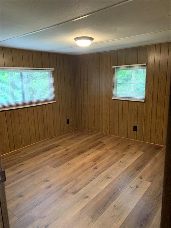 unfurnished room with hardwood / wood-style flooring and wooden walls