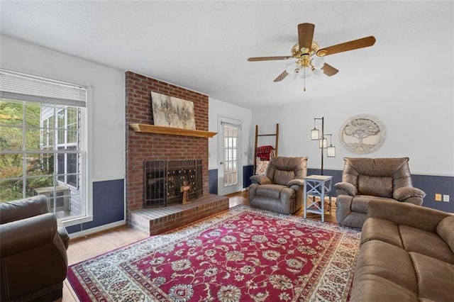 living room featuring a fireplace, plenty of natural light, wood finished floors, and ceiling fan