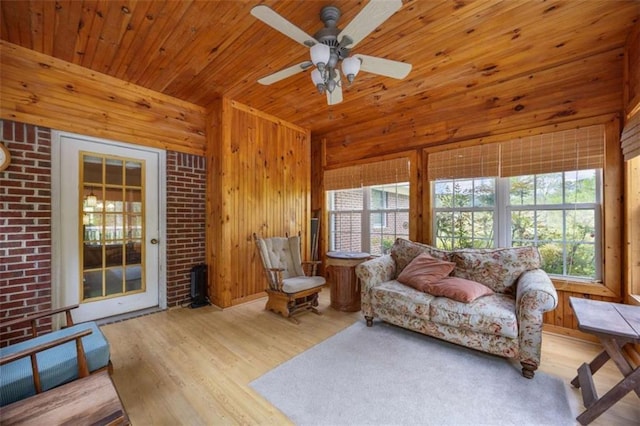 living area with wood finished floors, a healthy amount of sunlight, and wood walls