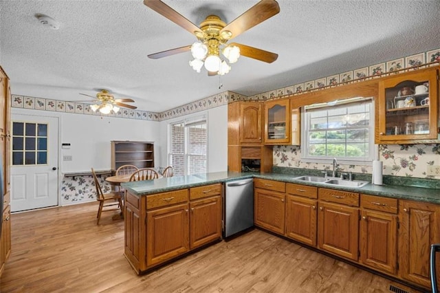 kitchen featuring dishwasher, brown cabinets, a sink, and a textured ceiling