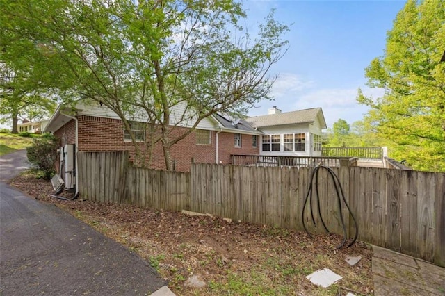 view of side of home with fence, a chimney, and brick siding