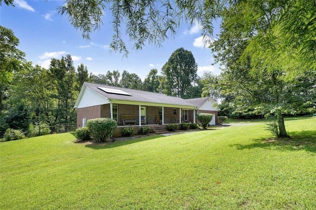 single story home with fence, a porch, a front yard, a garage, and solar panels