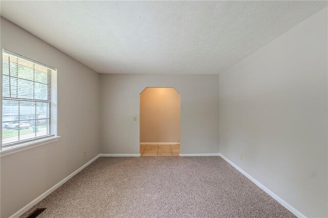 2247 Cherokee Valley Dr, Lithonia, GA 30058 - empty room featuring arched walkways, light carpet, and a textured ceiling