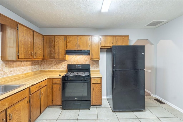 2247 Cherokee Valley Dr, Lithonia, GA 30058 - kitchen with black appliances, under cabinet range hood, brown cabinetry, decorative backsplash, and light countertops