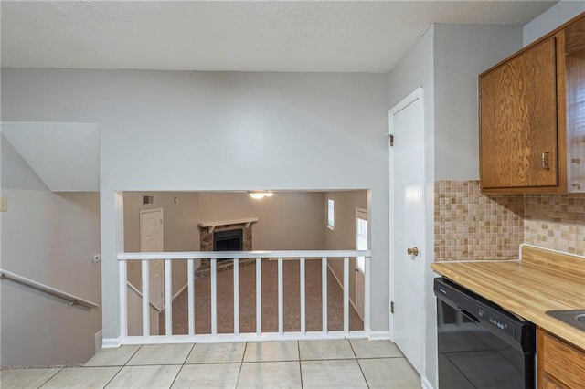 2247 Cherokee Valley Dr, Lithonia, GA 30058 - kitchen featuring black dishwasher, brown cabinetry, decorative backsplash, light countertops, and a fireplace