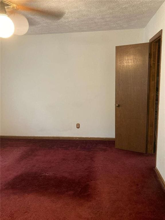 spare room with carpet flooring, a textured ceiling, and baseboards