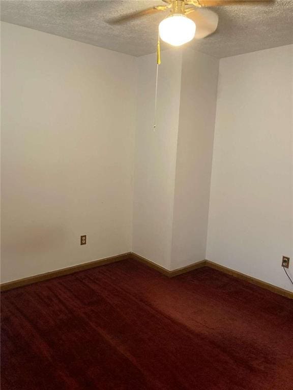 unfurnished room with baseboards, dark carpet, ceiling fan, and a textured ceiling