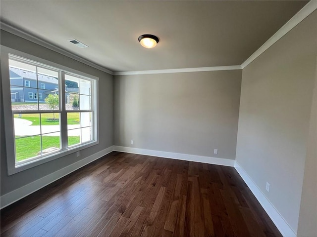 empty room featuring dark wood-type flooring and ornamental molding