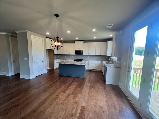 kitchen featuring white cabinets, a center island, decorative light fixtures, appliances with stainless steel finishes, and dark hardwood / wood-style flooring