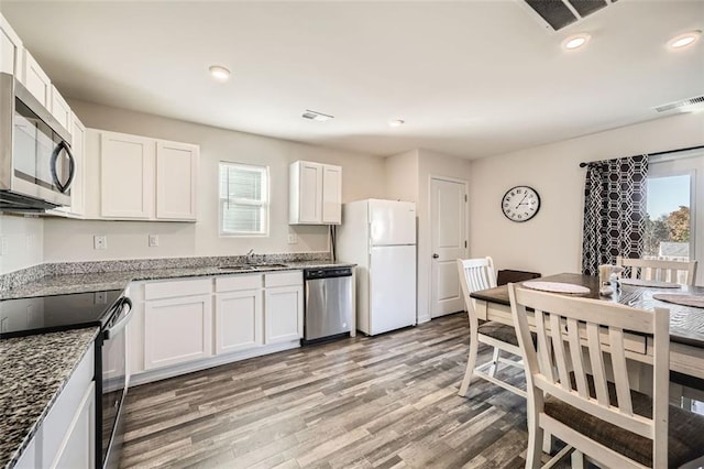 kitchen featuring white cabinets, appliances with stainless steel finishes, light stone counters, and a wealth of natural light