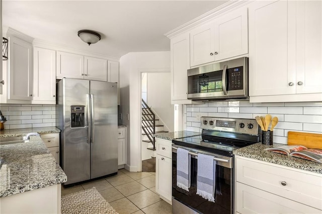 kitchen featuring sink, light stone countertops, white cabinets, and appliances with stainless steel finishes