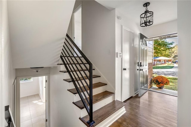 stairs with an inviting chandelier and hardwood / wood-style floors