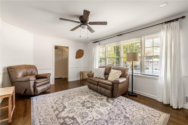 living room with dark hardwood / wood-style flooring, crown molding, and ceiling fan