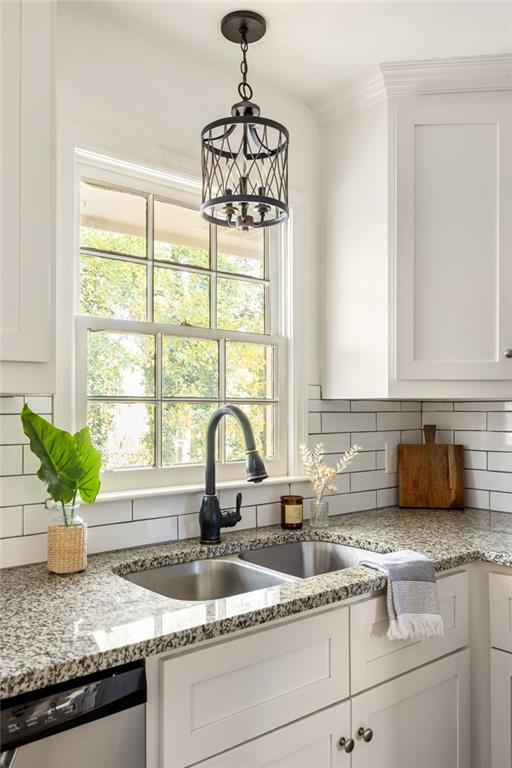 kitchen with white cabinetry, sink, stainless steel dishwasher, and backsplash