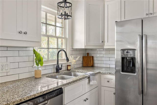 kitchen with sink, stainless steel appliances, white cabinets, and light stone countertops