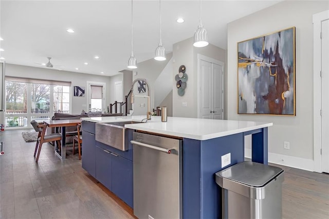 kitchen with ceiling fan, pendant lighting, sink, an island with sink, and blue cabinetry