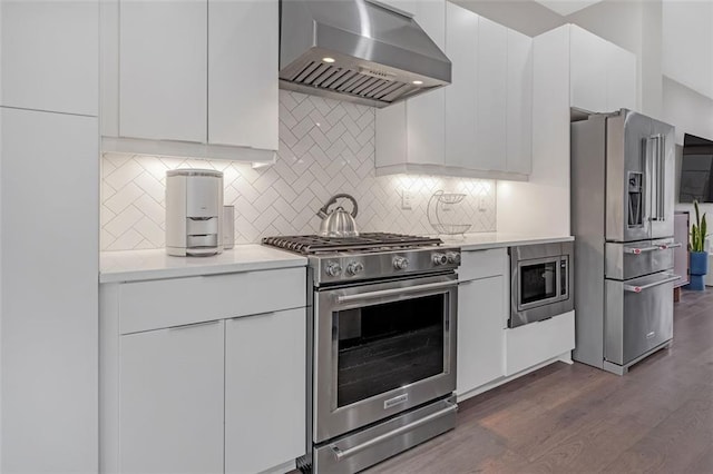 kitchen with premium appliances, white cabinetry, backsplash, dark hardwood / wood-style floors, and ventilation hood