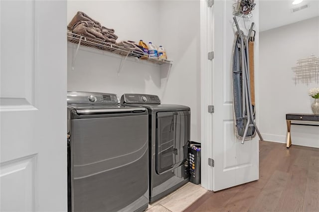 laundry room with independent washer and dryer and wood-type flooring