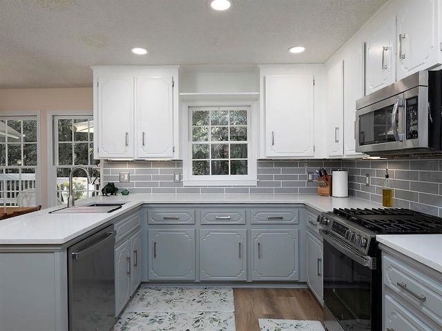 4601 Gann Xing SW, Smyrna, GA 30082 - kitchen with stainless steel appliances, gray cabinetry, a peninsula, a textured ceiling, and light countertops