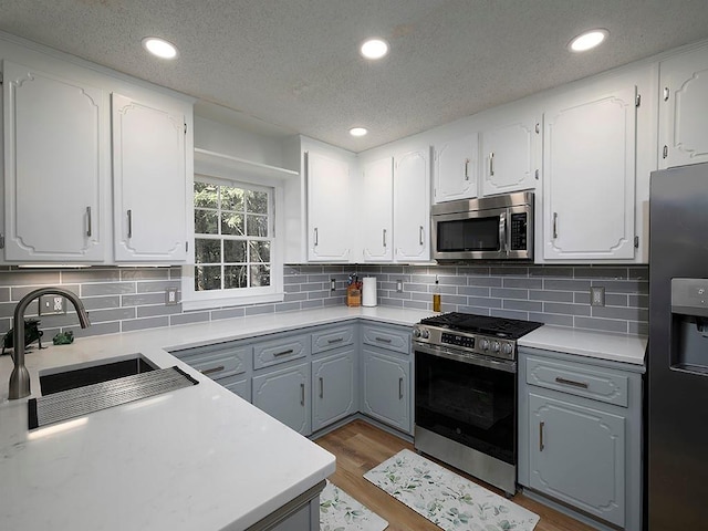 4601 Gann Xing SW, Smyrna, GA 30082 - kitchen featuring appliances with stainless steel finishes, a textured ceiling, wood finished floors, light countertops, and gray cabinets