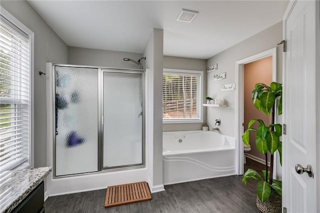 bathroom with a shower stall, wood finished floors, and a garden tub