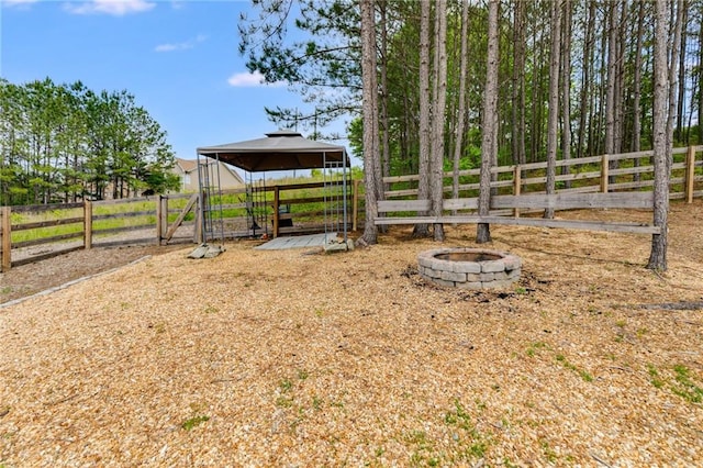 view of play area featuring an outdoor fire pit, fence, and a gazebo