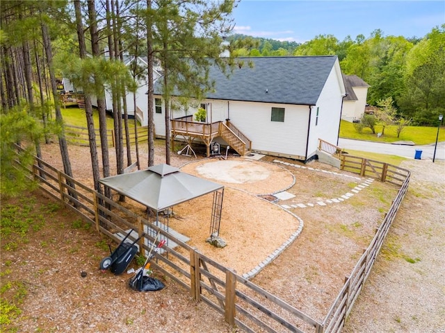 back of property with a wooden deck, a shingled roof, and fence